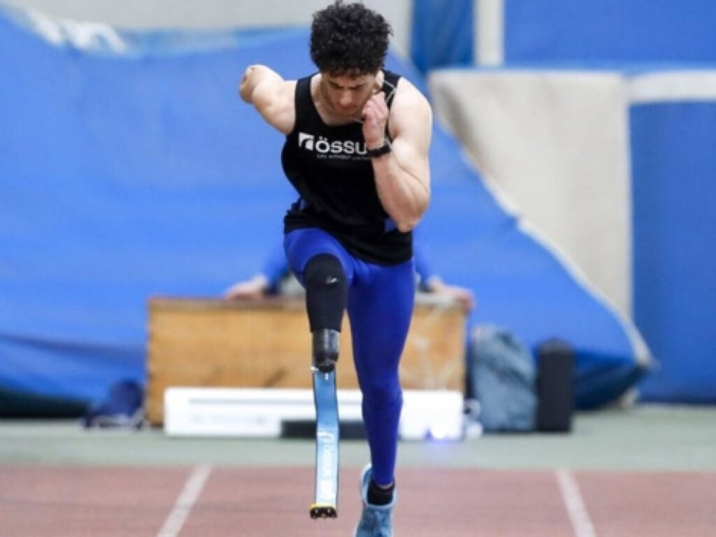 Atleta paralímpico con prótesis en entrenamiento en gimnasio cubierto.
