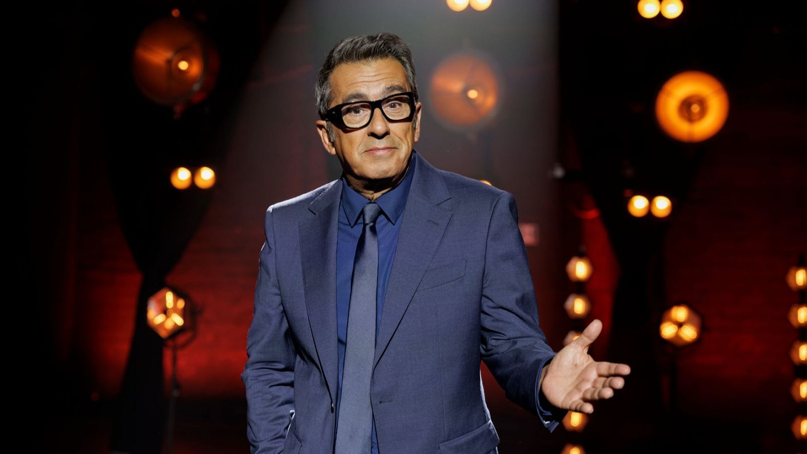 Andreu Buenafuente en un escenario, luciendo elegante traje azul, en un momento de su regreso tras s.
