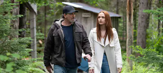 Escena de caminata en bosque con un hombre y una joven en Sullivan’s Crossing.