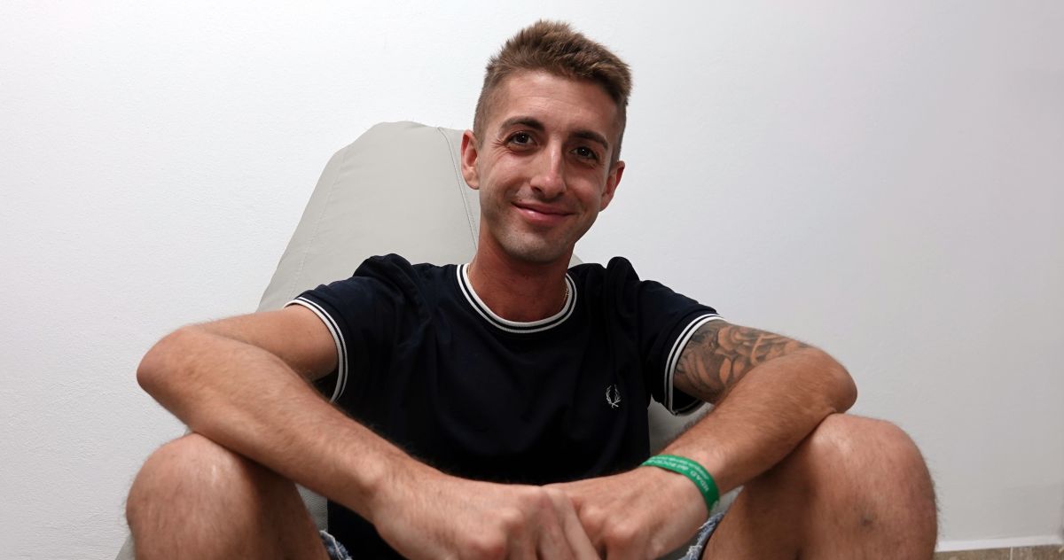 Joven con sonrisa, sentado en una sala, en honor a Xisco Quesada, símbolo de lucha contra el cáncer.