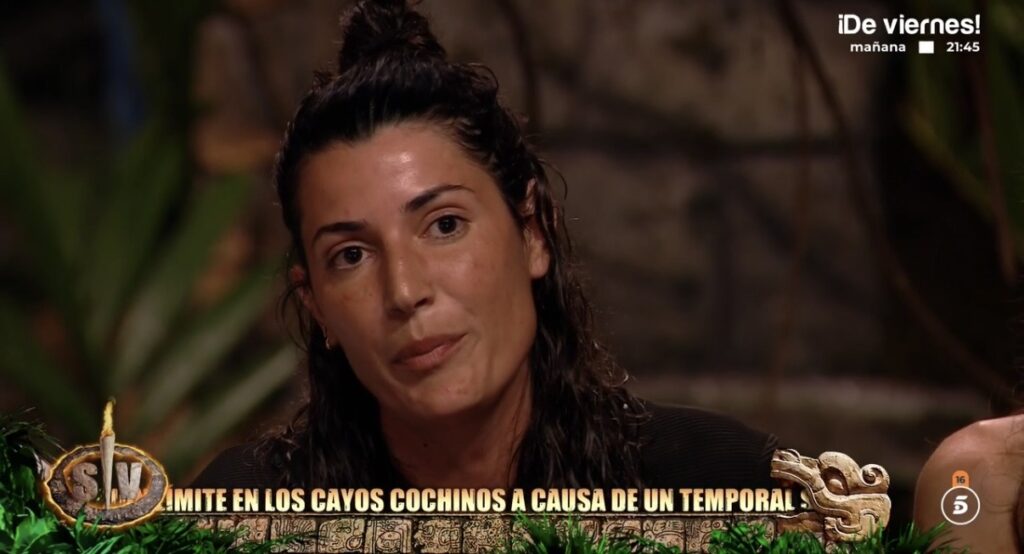 Una concursante de Supervivientes 2026 escucha en primer plano en la palapa, con el rótulo sobre el temporal en los Cayos Cochinos