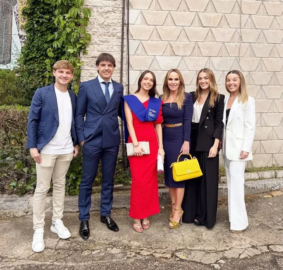 Martina, con banda de graduada y vestido rojo, rodeada de sus padres, Fernando Morientes y Victoria López, y sus tres hermanos